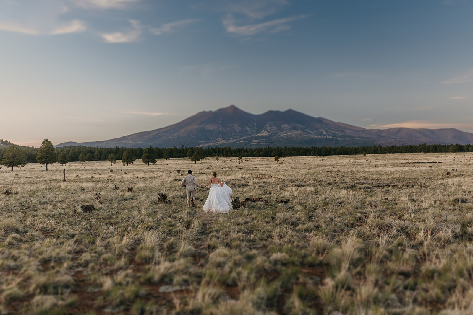 A couple runs through a field towards Humphreys Peak.