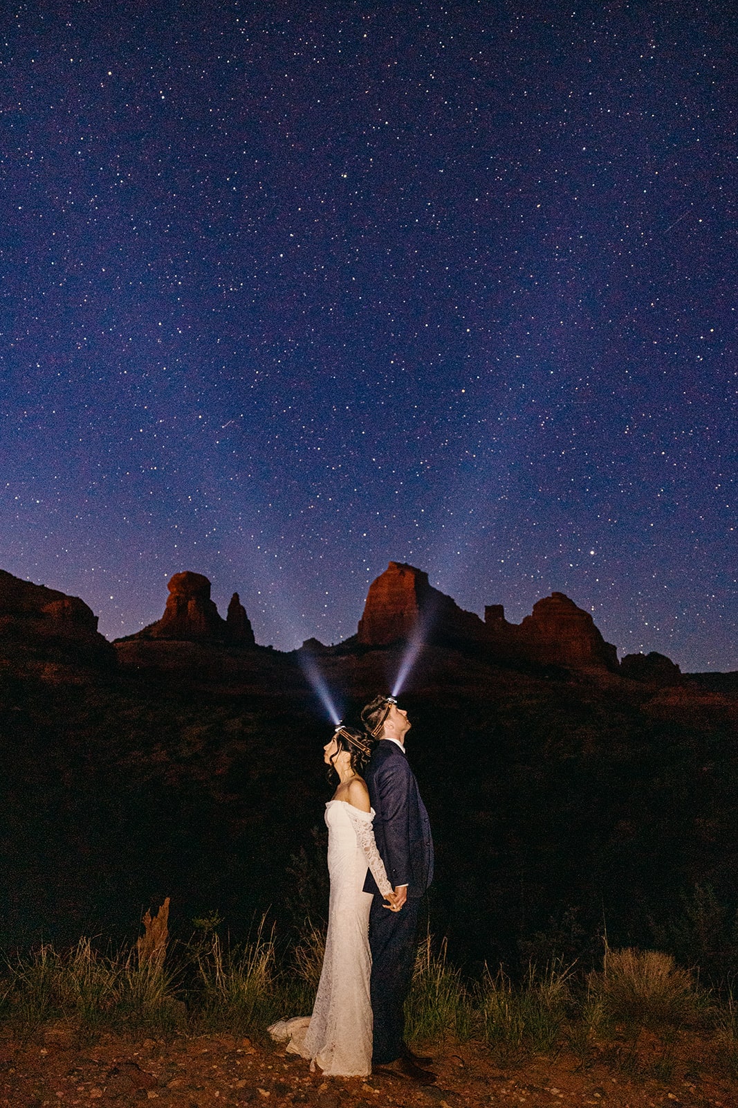 Bride and groom wear headlamps under a starry sky at the end of their family elopement day in Arizona.
