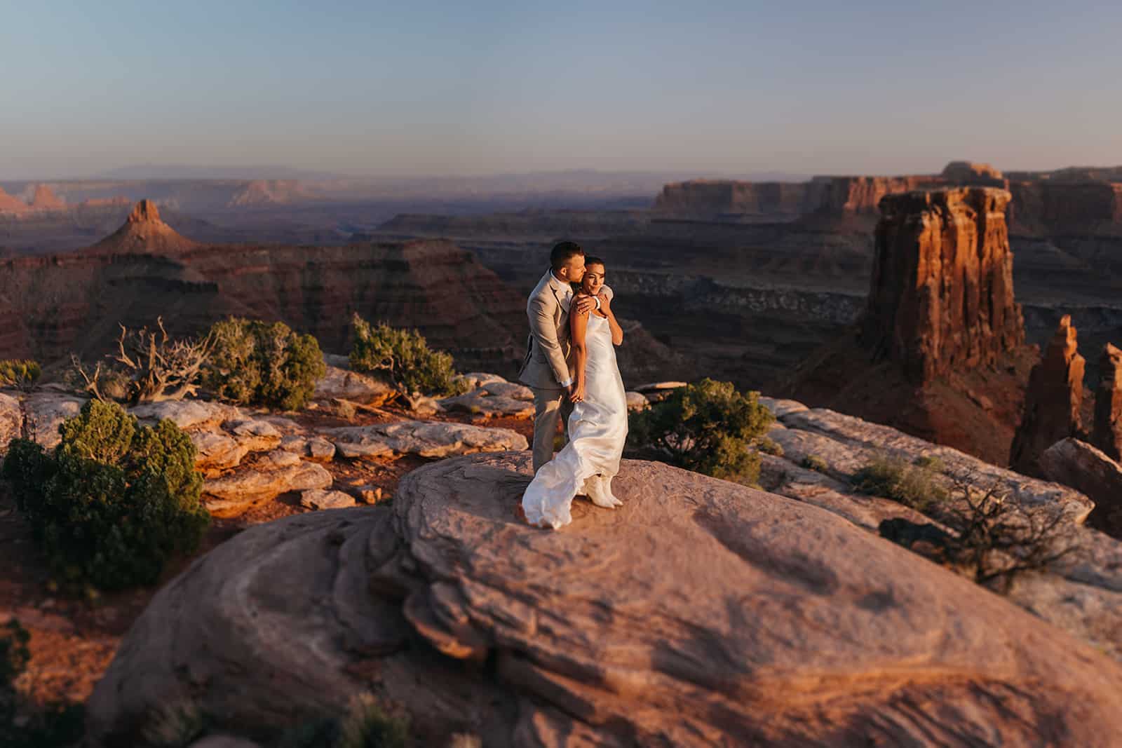 Bride and groom hug on a desert vista during their elopement with friends.