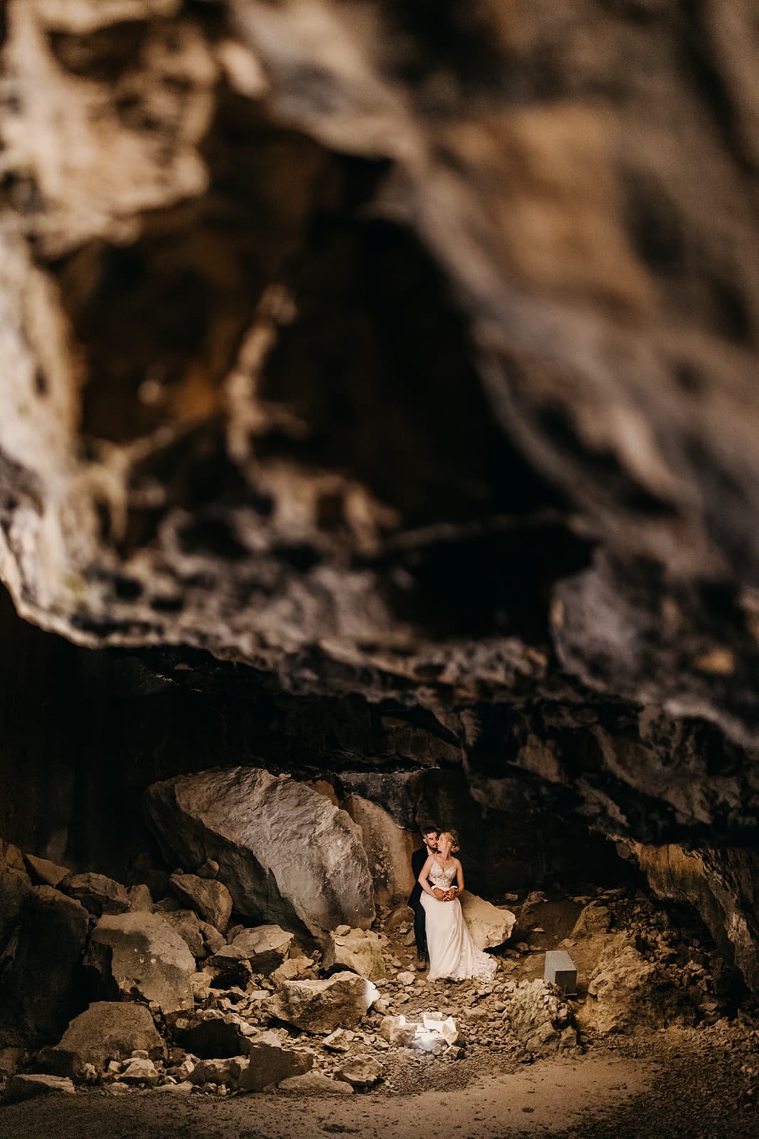 A couple poses for a photo in a cave at night.