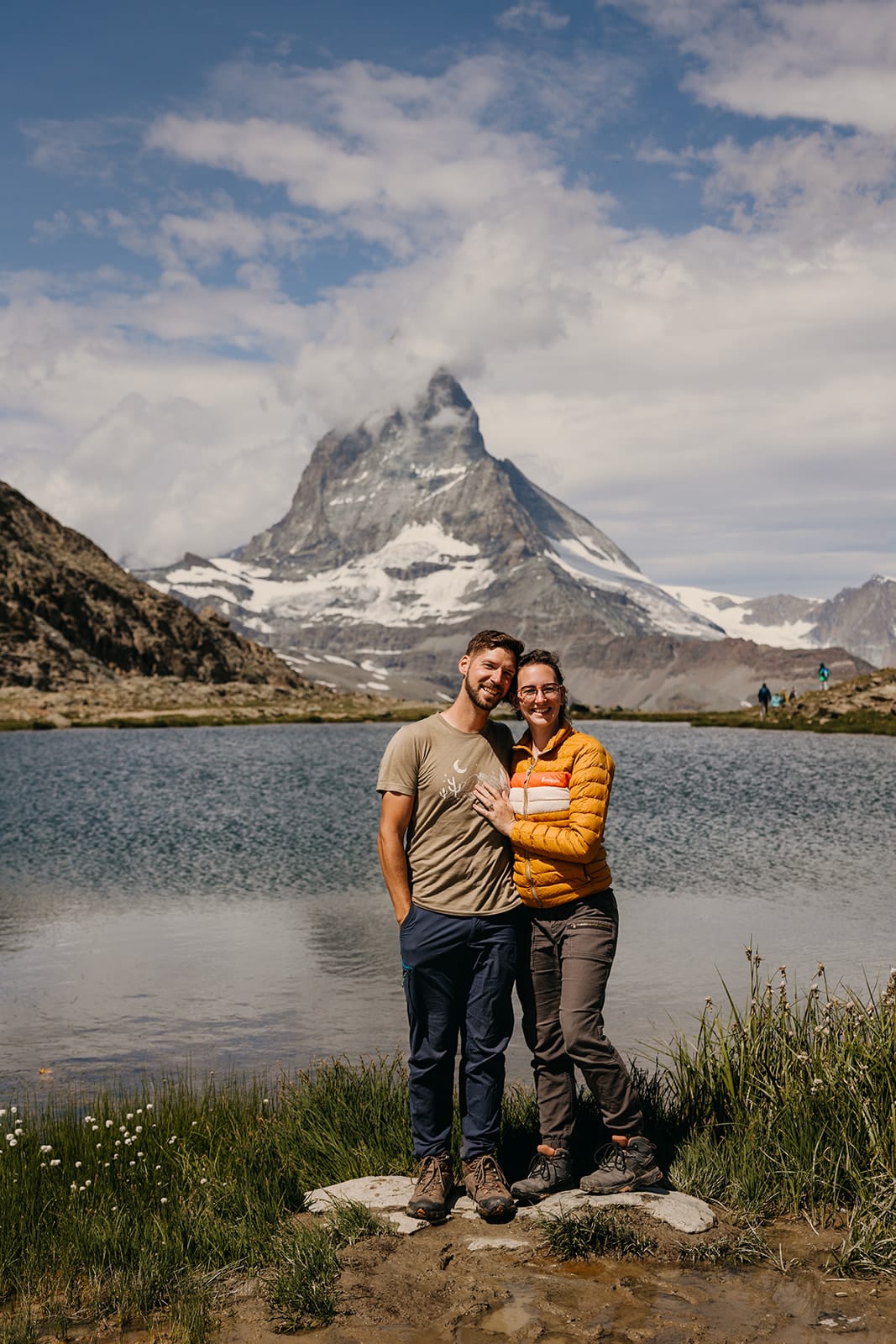 A husband and wife photography team pose for a portrait in front of the Matterhorn.