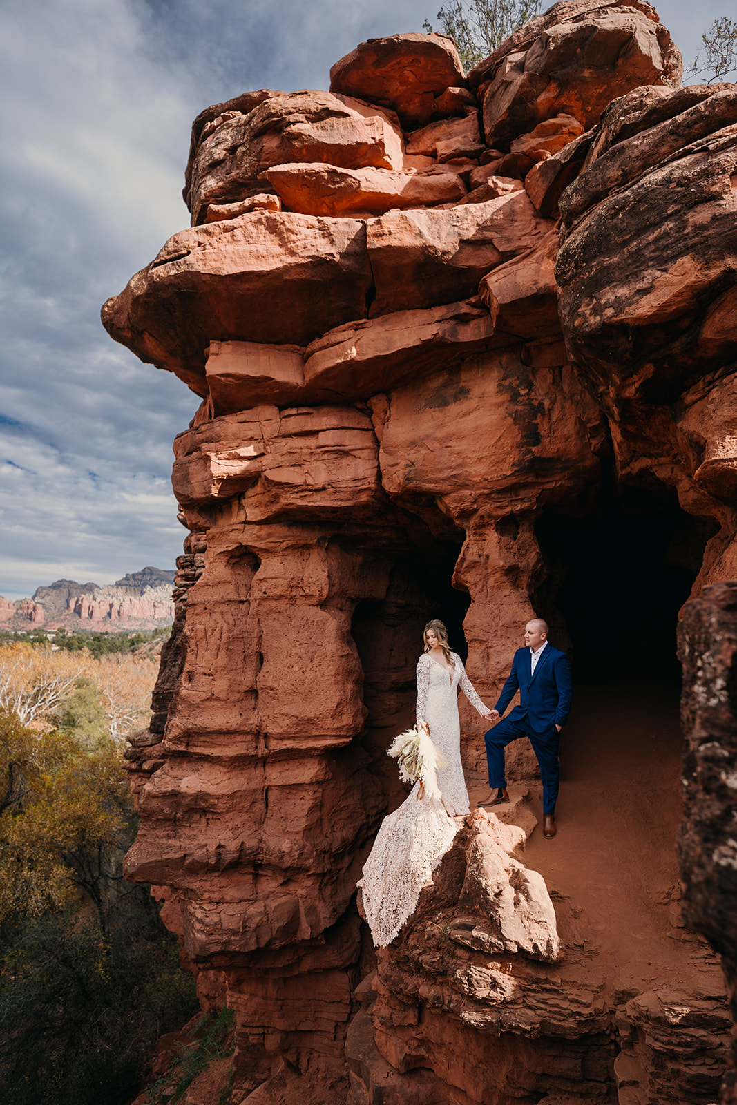 Newlyweds stand on a red rock ledge during their adventure elopement in Sedona, Arizona.