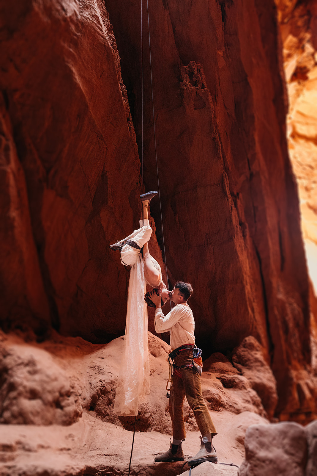 A bride flips upside down on her rope to kiss her groom in a slot canyon.