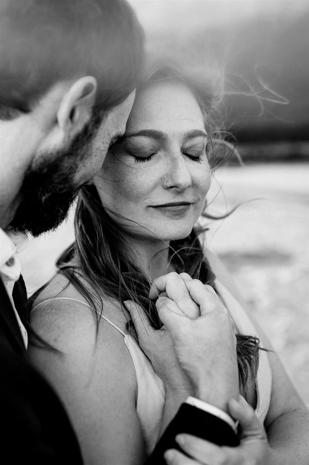 A close black and white image of a bride and her husband.