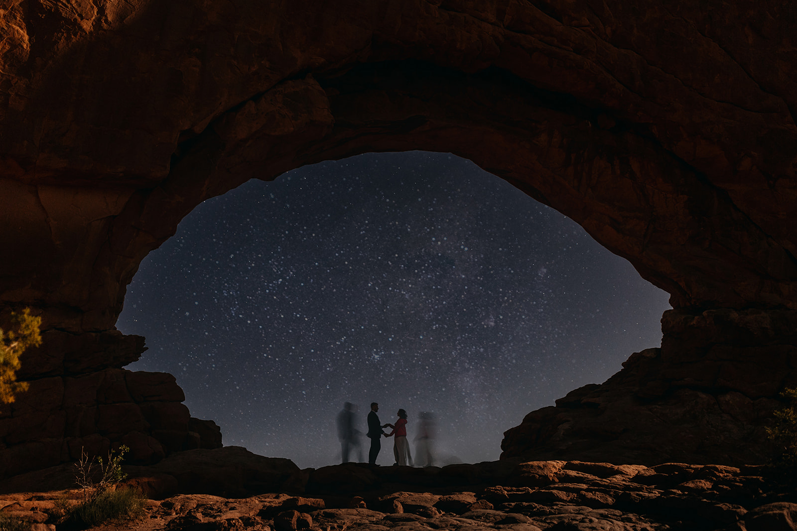 An image of a couple under an arch with them holding hands in the center and stars in the background