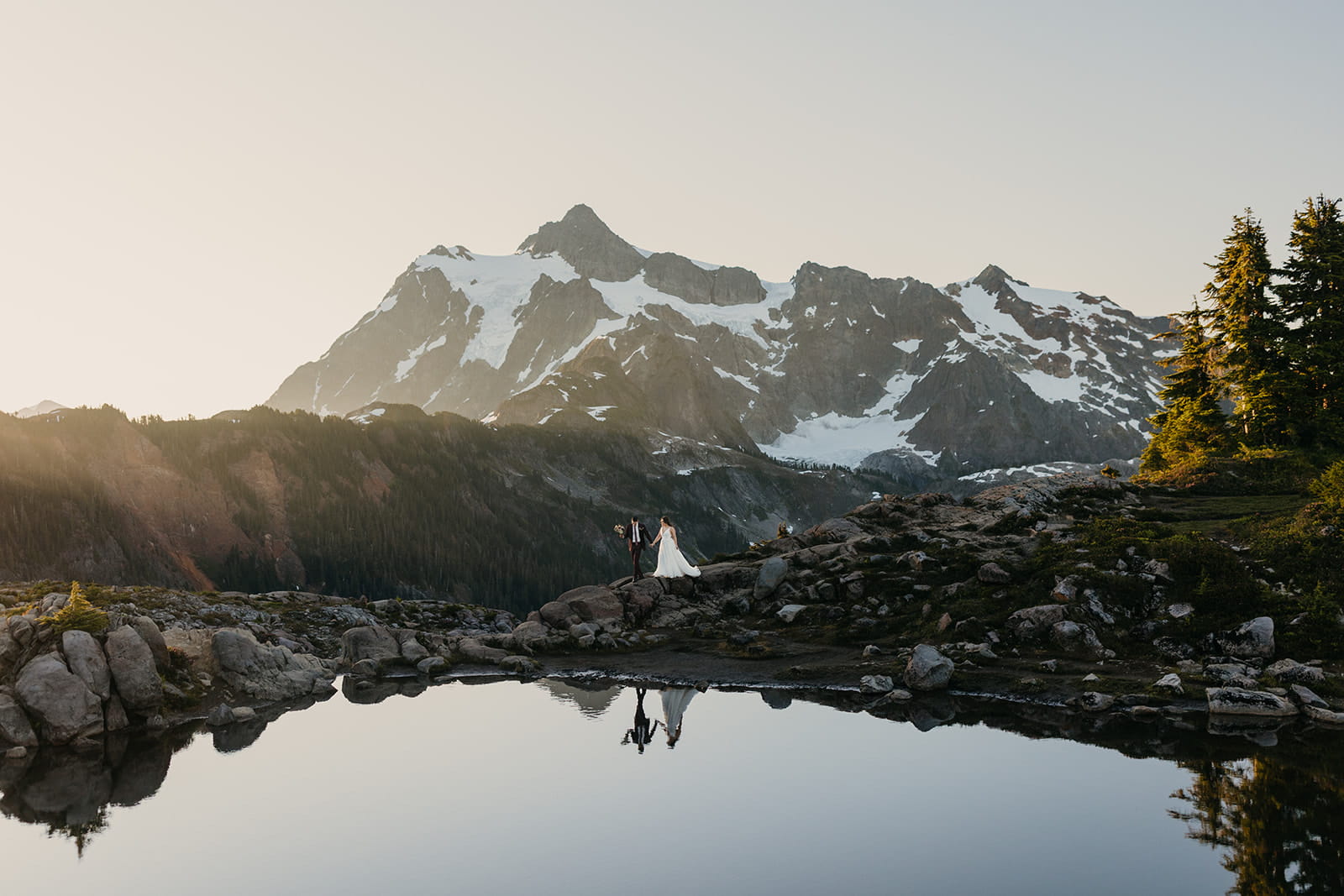 Newlyweds stand by a reflection lake in front of Mount Shuksan during their Airbnb elopement near Huntoon Point.