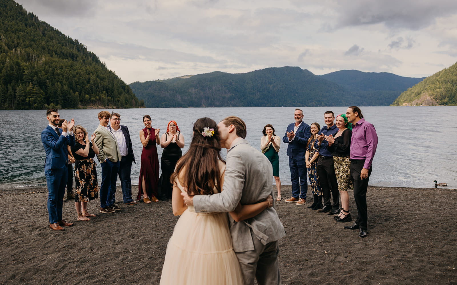 Groom kisses bride on the cheek during their elopement with family on the Olympic Peninsula.
