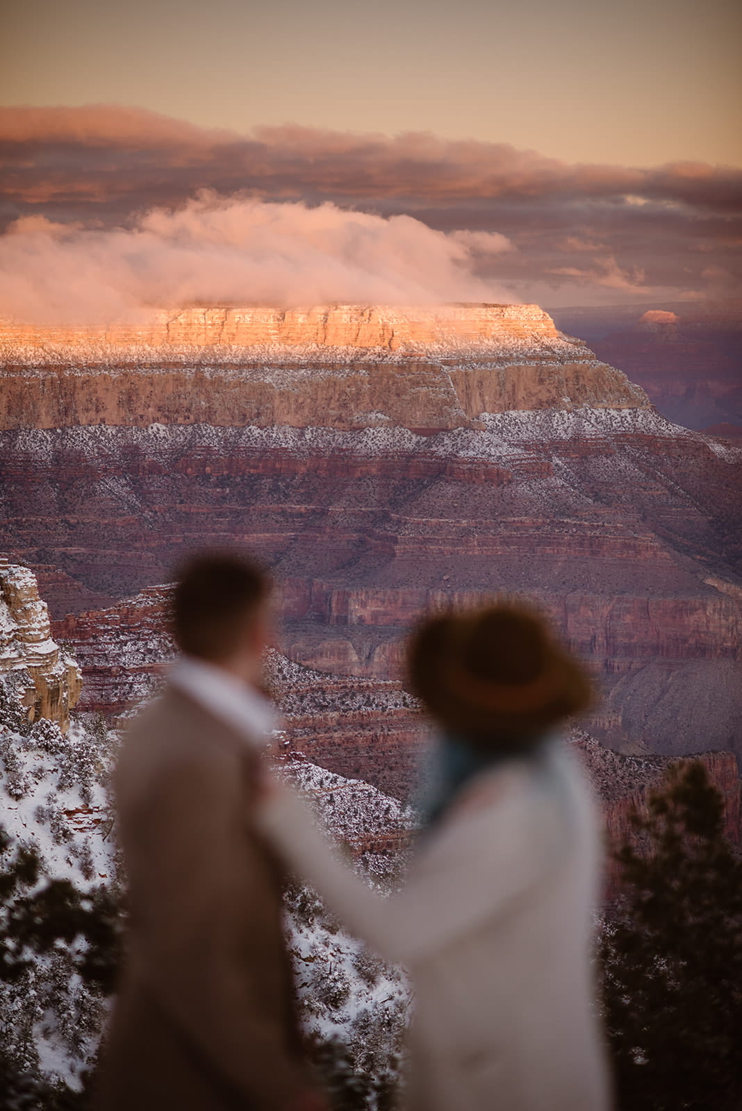 Newlyweds look out at a snowcapped red rock landscape during their winter elopement.