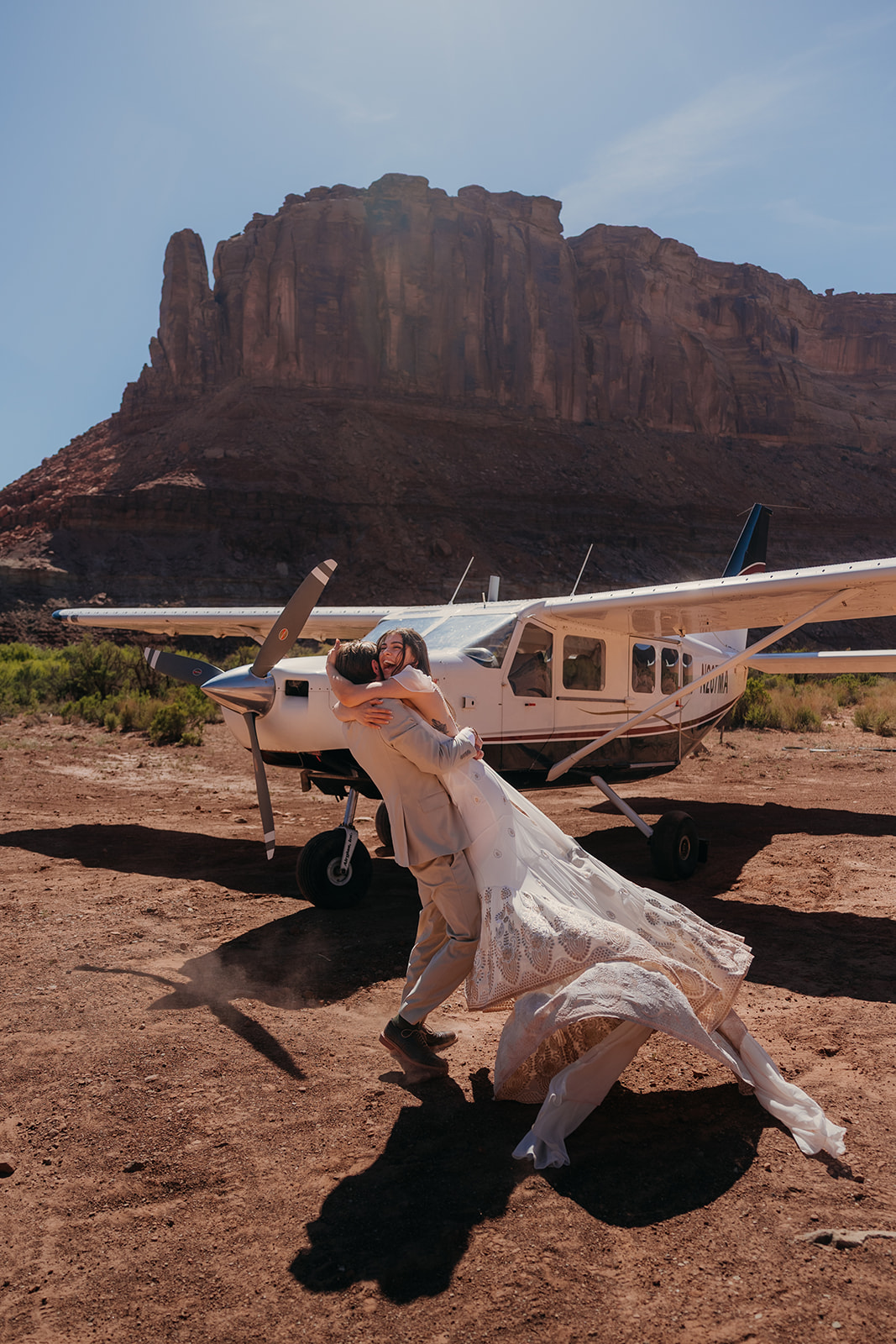 A couple spins together after their first look in front of a private plane in a Moab canyon.